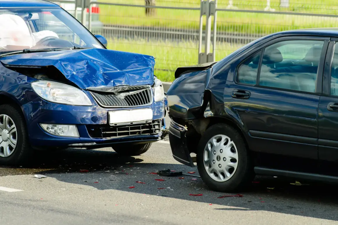 Wypadek drogowy. Niebieski i czarny samochód po kolizji. Widać uszkodzenia, poduszki powietrzne. Zasada 3 sekund nie została zachowana.