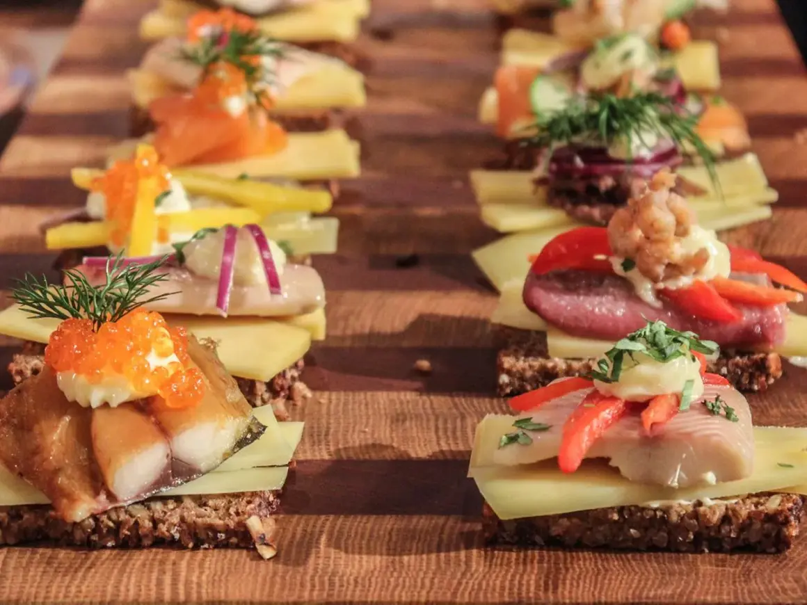 Reihe von appetitlichen Smørrebrød mit Fisch, Kaviar und Gemüse – perfektes schnelles Fingerfood für jeden Anlass.