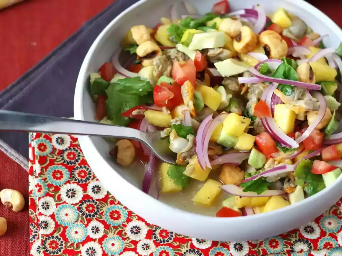 Delicioso ceviche de berberechos con mango, aguacate, tomate y cebolla morada. Una explosión de sabor fresco y vibrante.