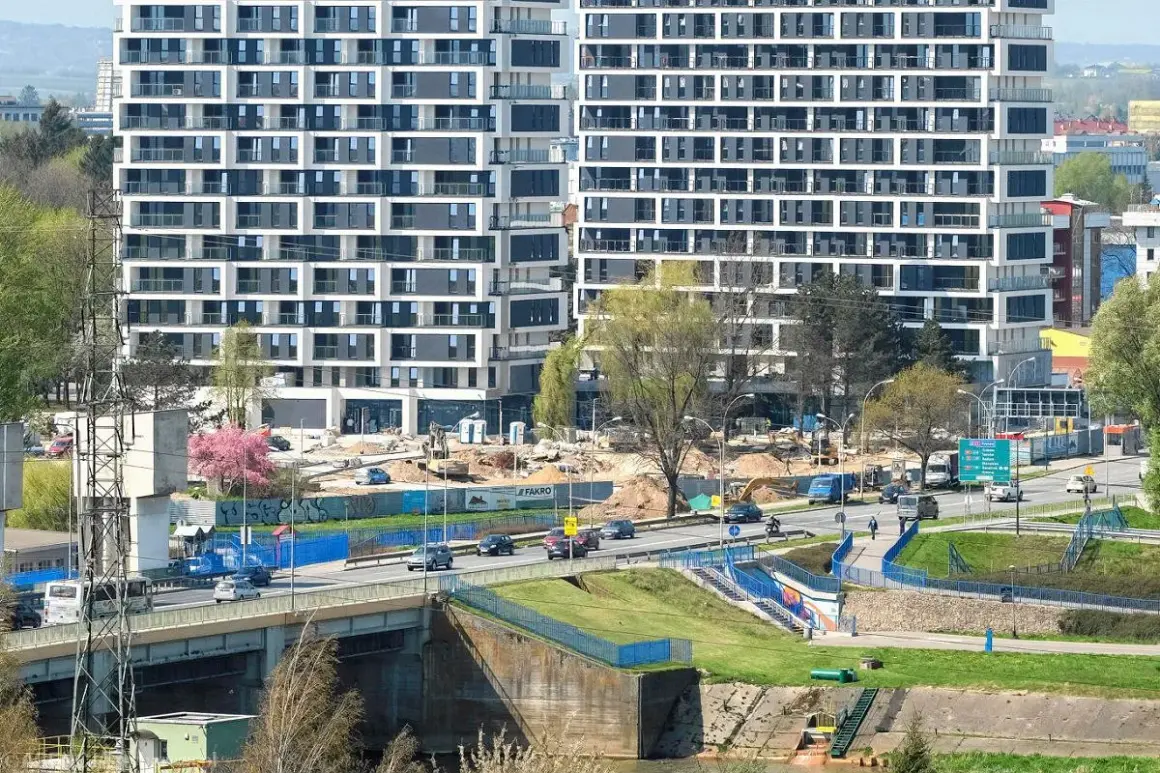 Nowe mieszkania do wynajęcia Rzeszów. Nowoczesne apartamentowce w budowie, ruchliwa droga i most.