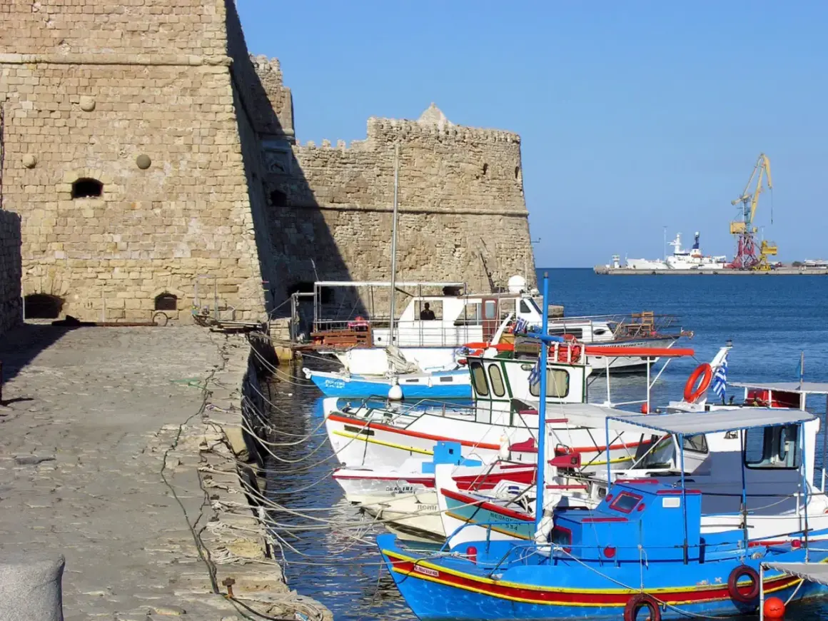 Port w Heraklionie, Kreta. Wrzesień, idealna temperatura na rejs. W tle twierdza, łodzie rybackie i dźwig portowy.