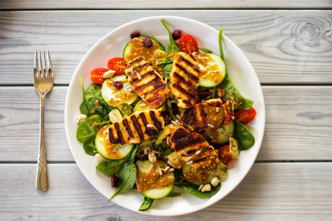 Pyszna sałatka z grillowanym halloumi, rukolą, pomidorkami, ogórkiem i słonecznikiem, polana sosem musztardowym.
