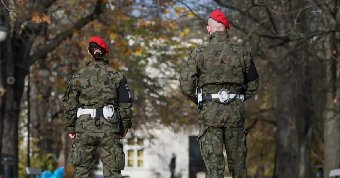 Dwóch żołnierzy w mundurach moro i czerwonych beretach stoi na tle drzew. Czy wojsko może zabrać samochód? To pytanie pozostaje bez odpowiedzi.