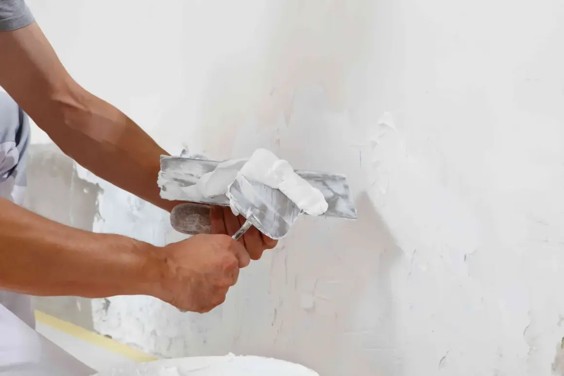 Man applying enfoscado de mortero a una pared con una llana.