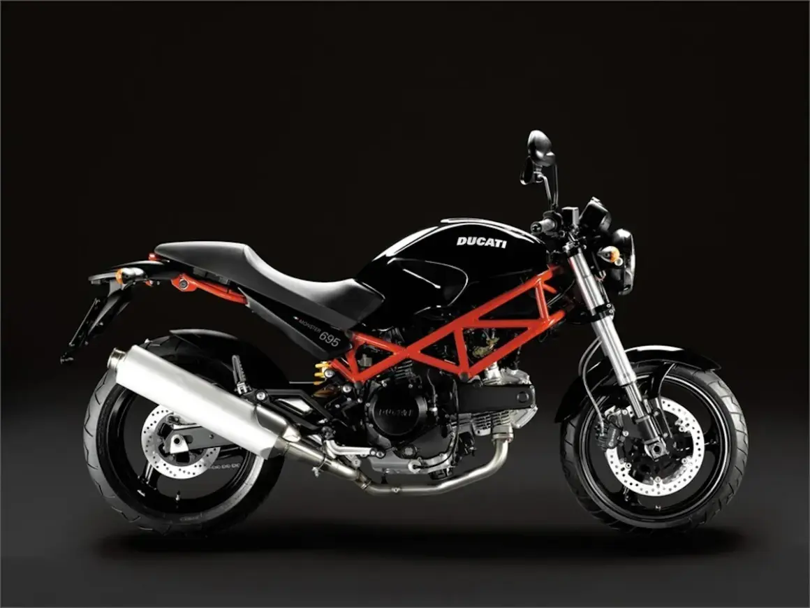 Ducati Monster 695 ficha técnica: una moto negra con chasis tubular rojo, asiento negro y escape plateado, lista para la carretera.