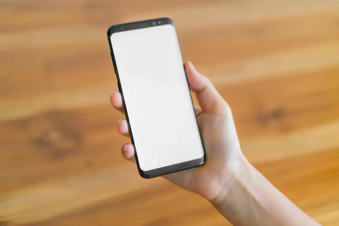 Dłoń trzyma smartfon z pustym ekranem. Czekam na ważny telefon, bo mam dyżur.