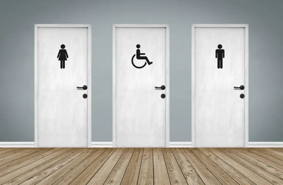 Trois portes blanches avec des pictogrammes : femme, homme et une porte pmr au centre.