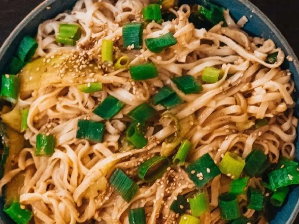 Schüssel mit Udon-Nudeln, garniert mit Frühlingszwiebeln und Sesam. Ein einfaches Udon-Nudel-Rezept, das schnell zubereitet ist.