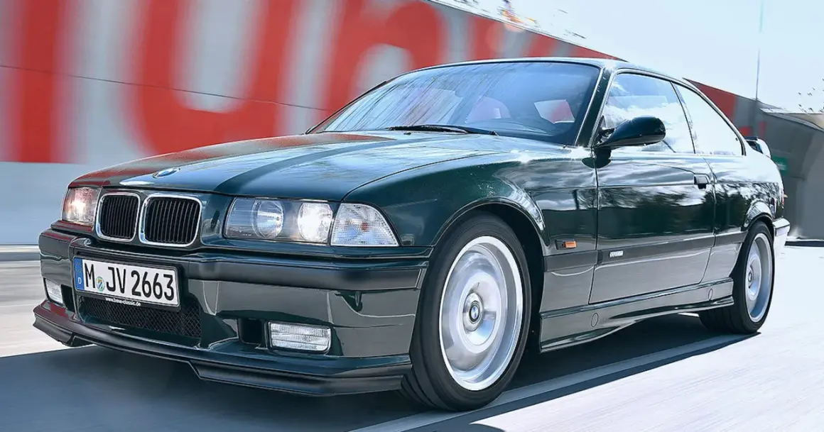 Klasyczne BMW E36 w kolorze ciemnej zieleni pędzi po drodze.