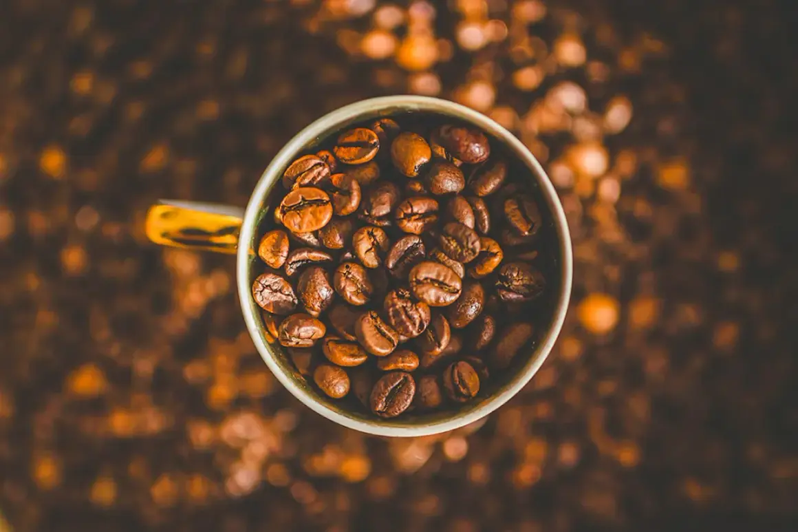 En kopp fylld med rostade kaffebönor, redo att ge dig en rejäl koffeinhaltig kaffeupplevelse.
