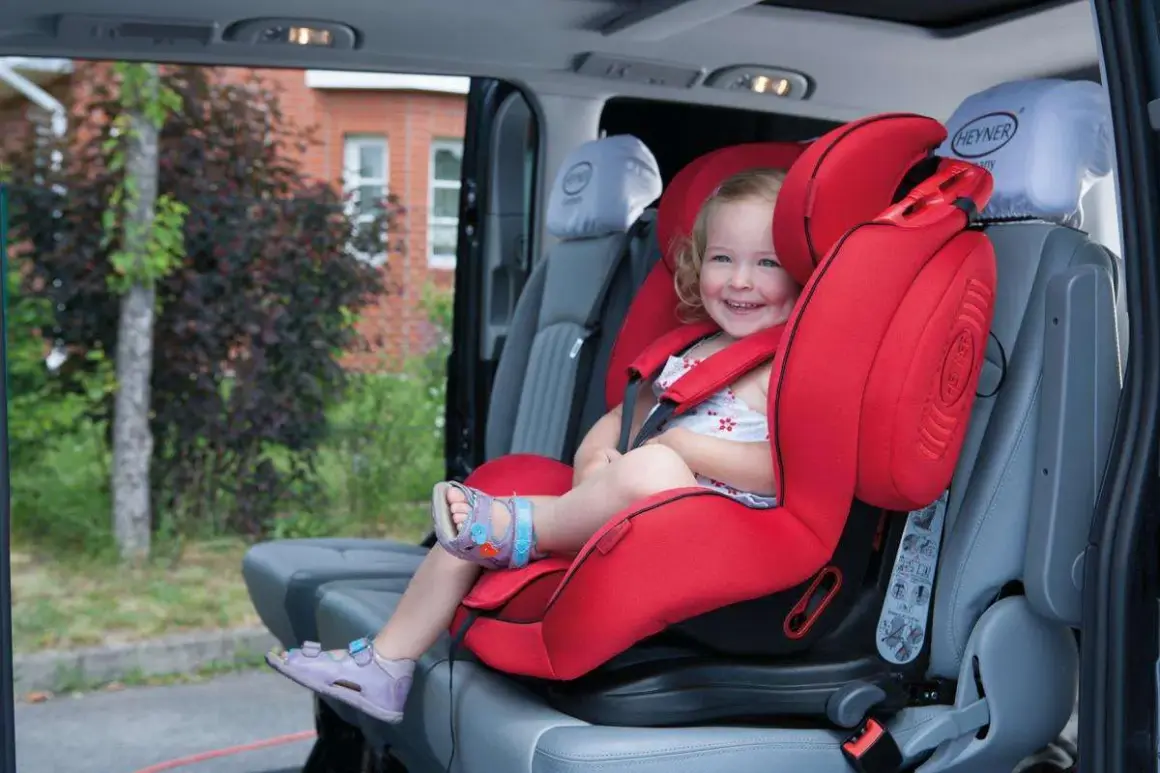 Ein lächelndes Kind sitzt sicher in einem roten Kindersitz im Auto. Perfekt für den nächsten Ausflug oder als Taxi Kindersitz.