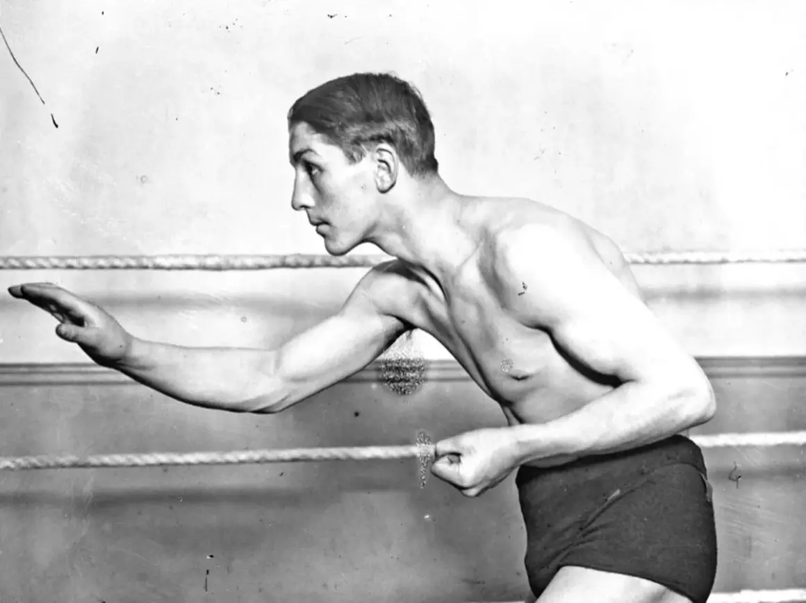 Georges Carpentier, a legendary boxer, poses in the ring, his muscular physique ready for action.