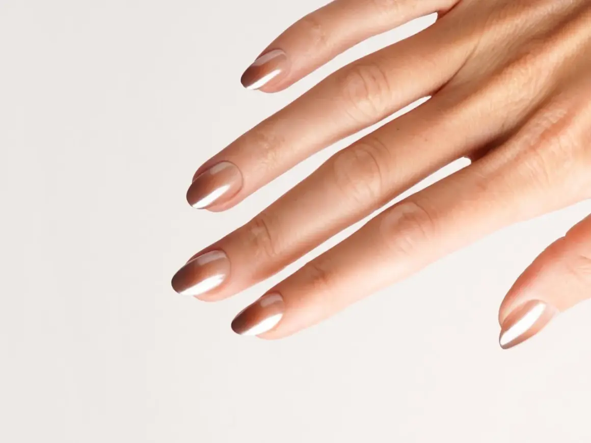 Eine Hand mit eleganten Nägeln im Ombre-Look, braun und weiß verlaufend.