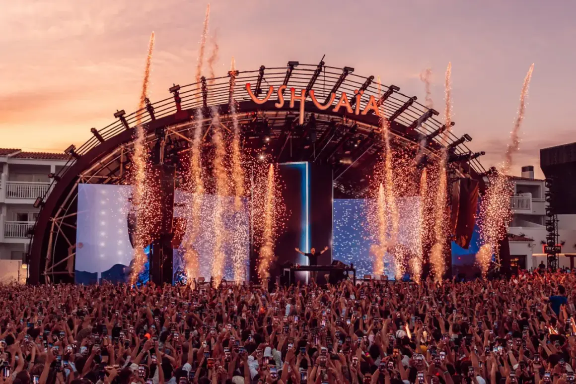 Un'esplosione di fuochi d'artificio illumina il palco di Ushuaïa Ibiza, dove un DJ incanta la folla. Un evento indimenticabile!