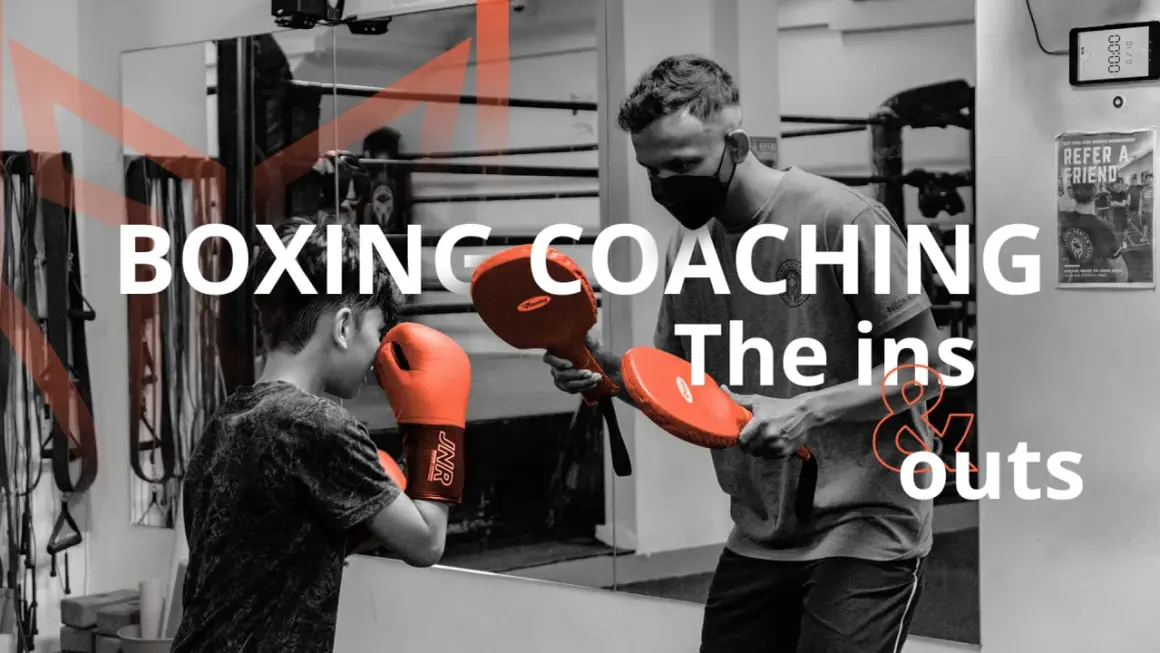 A coach demonstrates boxing techniques to a young boxer, highlighting the ins and outs of coaching boxing.