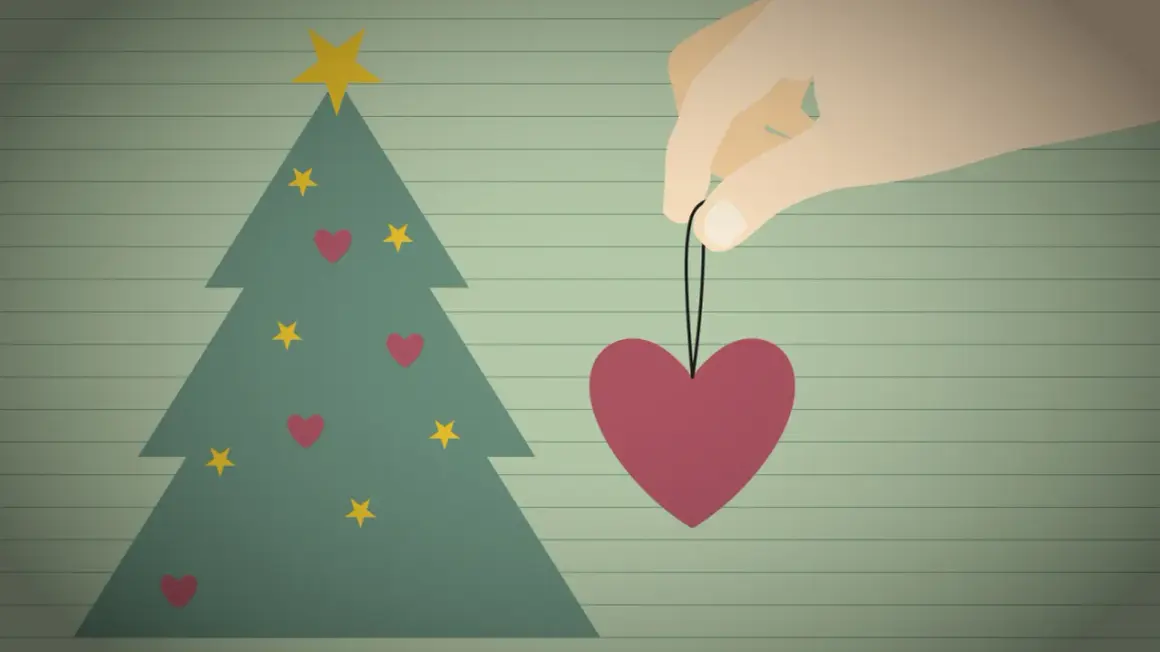 Ein Herz als Weihnachtsbaumschmuck, gehalten von einer Hand, symbolisiert eine besinnliche Weihnacht voller Liebe.