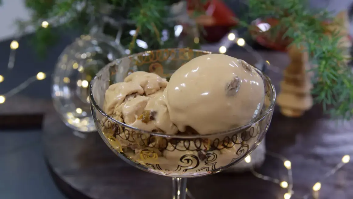 En skål med krämig kokosglass, perfekt för ett hemmagjort kokosglass recept. Julbelysning och gran i bakgrunden.