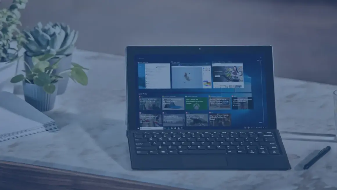 Nowoczesny laptop z klawiaturą i ekranem dotykowym, obok rośliny i stosu papierów. Idealny do pracy, gdy środek trwały od jakiej kwoty jest potrzebny.