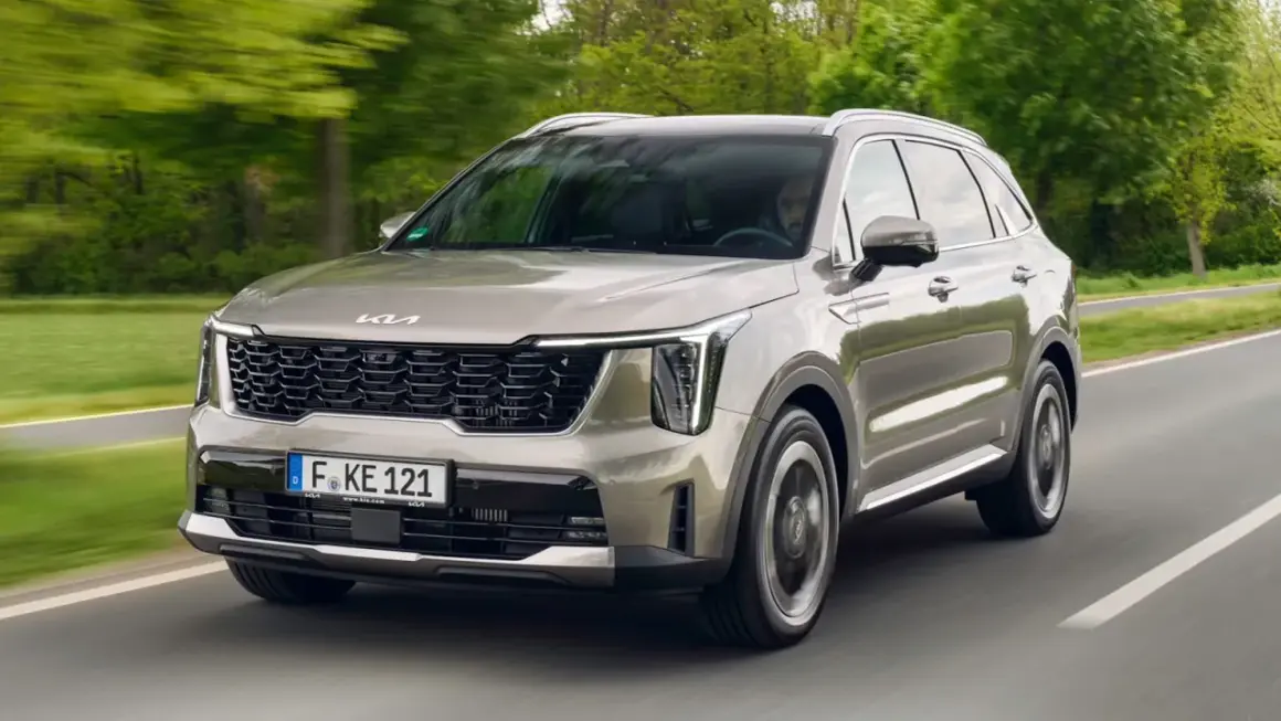 Un Kia Sorento preparado para la aventura, con su diseño moderno y elegante, avanza por una carretera rodeada de vegetación.