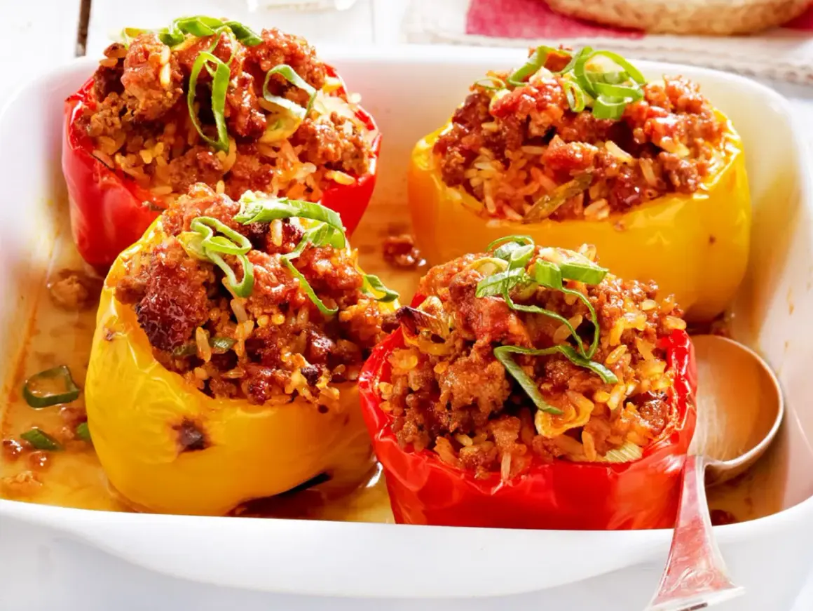 Gefüllte Paprika mit Hackfleisch und Reis, garniert mit Frühlingszwiebeln, in einer Auflaufform.