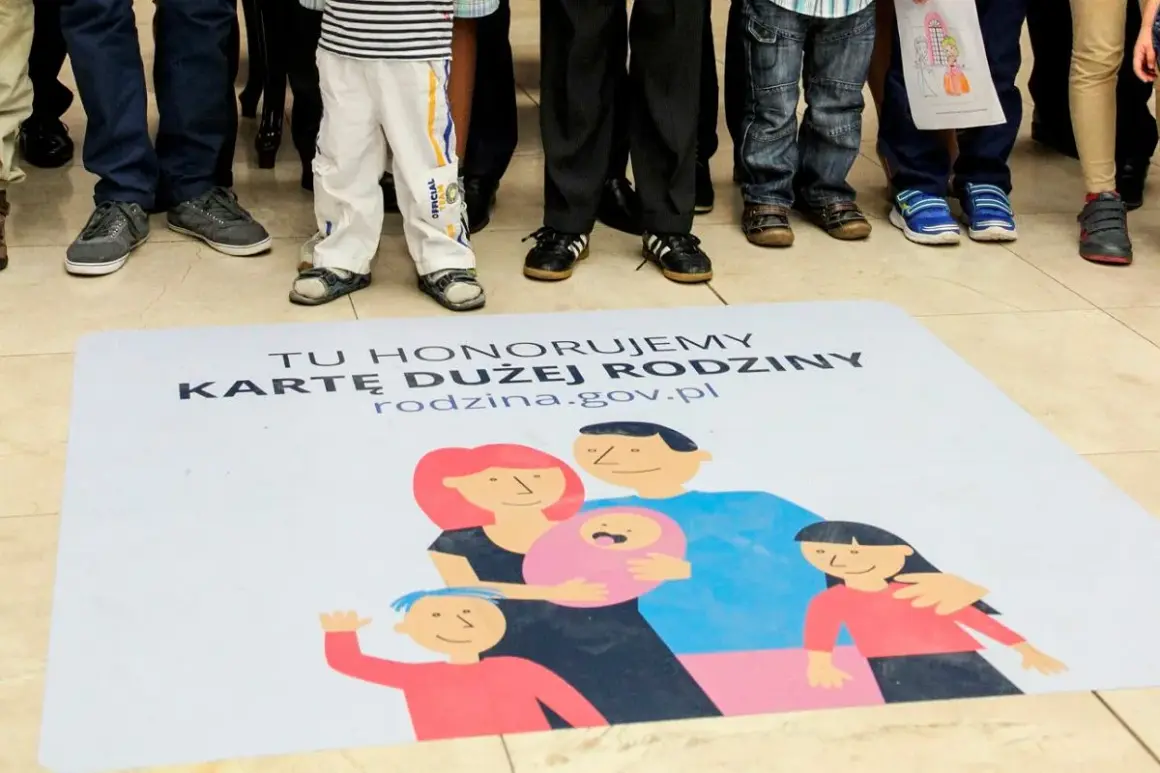 Na macie z napisem "Tu honorujemy Kartę Dużej Rodziny" widnieje rysunek rodziny. Dzieci i dorośli stoją wokół.