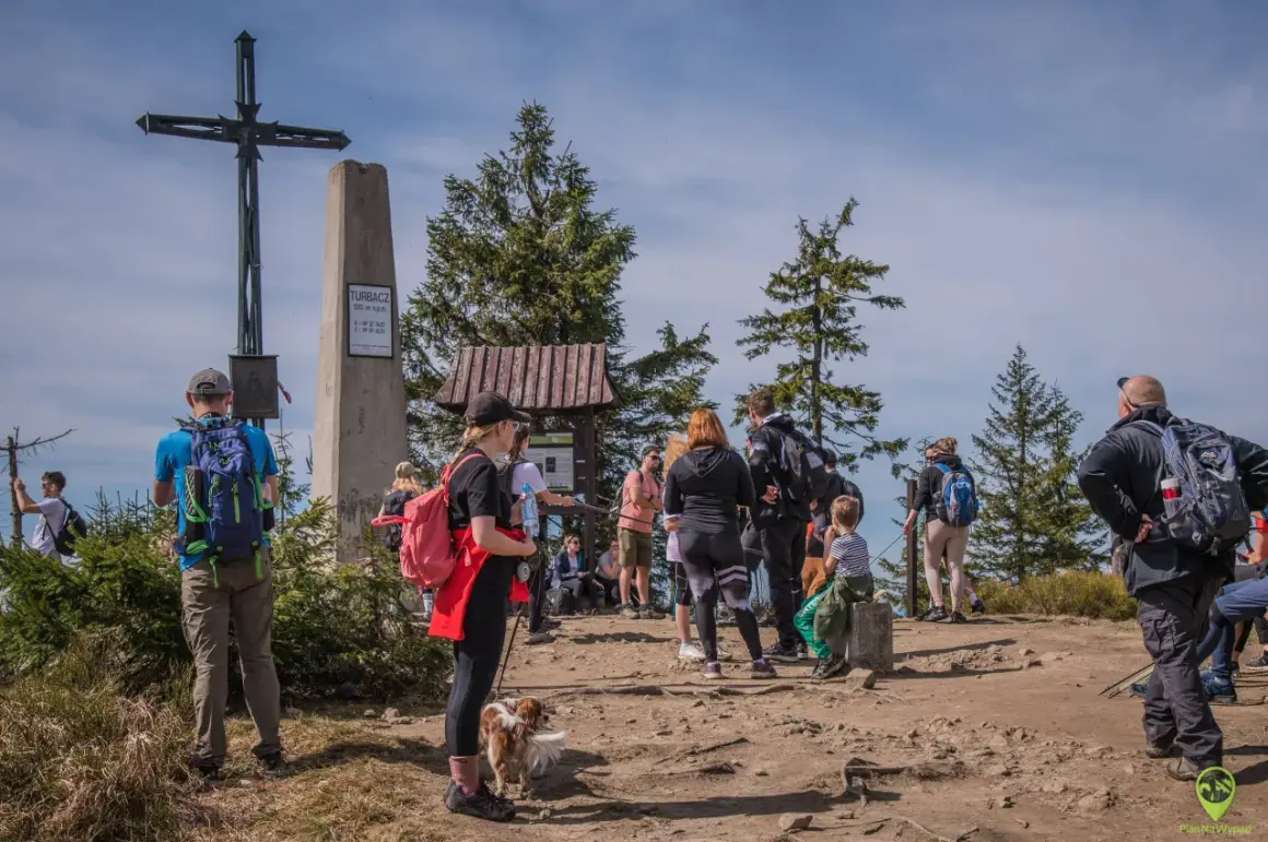 Grupa turystów na szczycie Turbacz (1310 m n.p.m.). Zastanawiają się, ile jeszcze idzie się do celu.