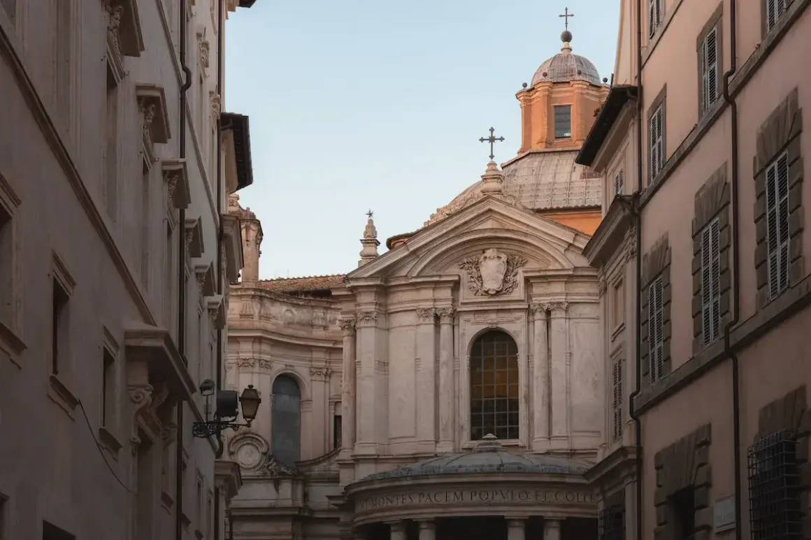 La facciata barocca della chiesa di Santa Maria della Pace si staglia tra palazzi romani, con la sua cupola imponente e le decorazioni scultoree.