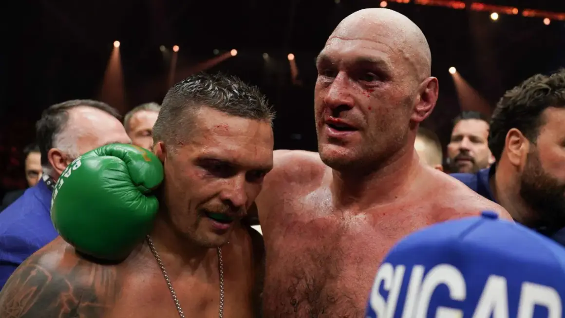 Två boxare, en med blod i ansiktet, omfamnar varandra. Tyson Fury vikt är en viktig faktor i deras matcher.