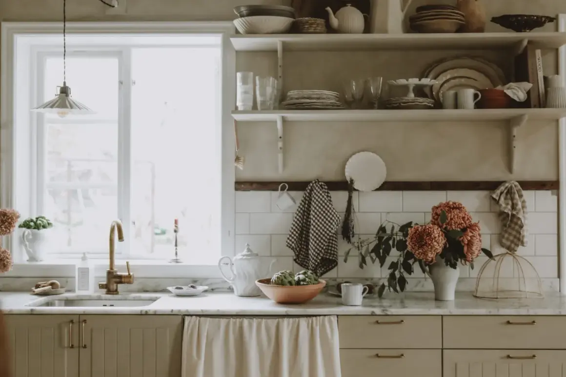 Köksbänk med diskho, kran och blommor. Skåpluckor i ljusbeige färg, redo att måla luckor för en ny stil.