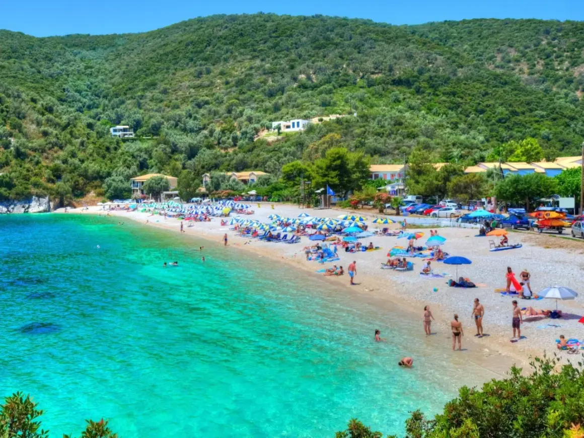 Piękna plaża z turkusową wodą, zielone wzgórza i domki w tle. To idealne miejsce na wakacje na Karaibach, wyspy zapraszają do odpoczynku.