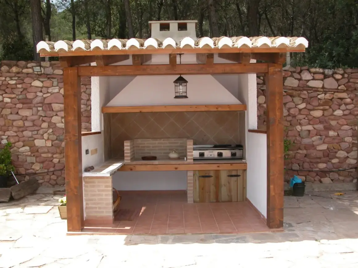 Barbacoa de obra con estructura de madera y tejado de tejas. Ideal para aprender como hacer una barbacoa de obra y disfrutar del exterior.