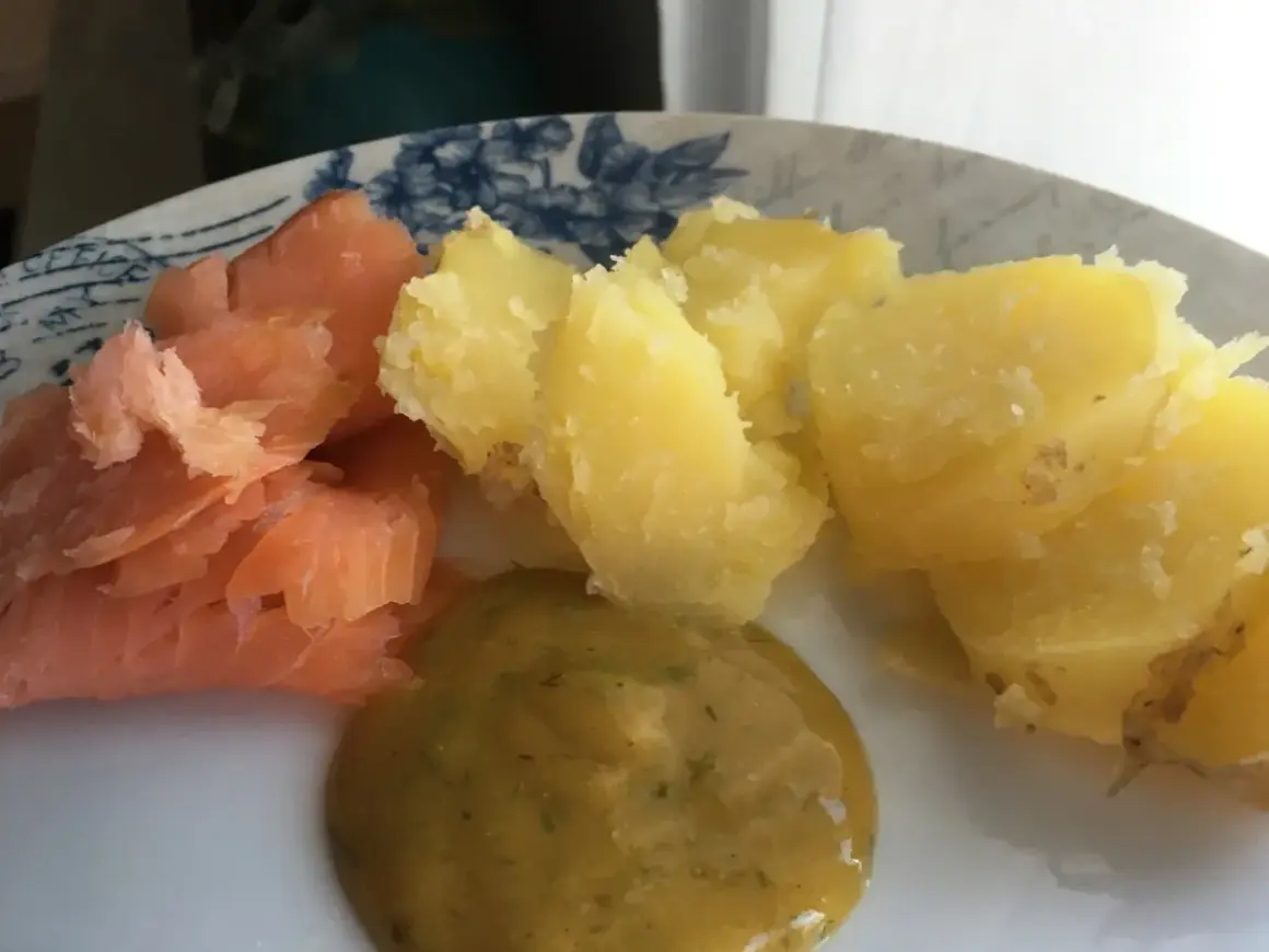 En tallrik med gravad lax, kokt potatis och en klick gravlaxsås. Perfekt för ett snabbt och gott recept.