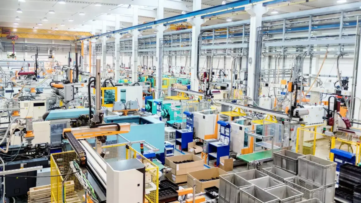 Nowoczesna hala produkcyjna z liniami maszyn, robotami i taśmociągami. Efektywne zarządzanie produkcją w akcji.