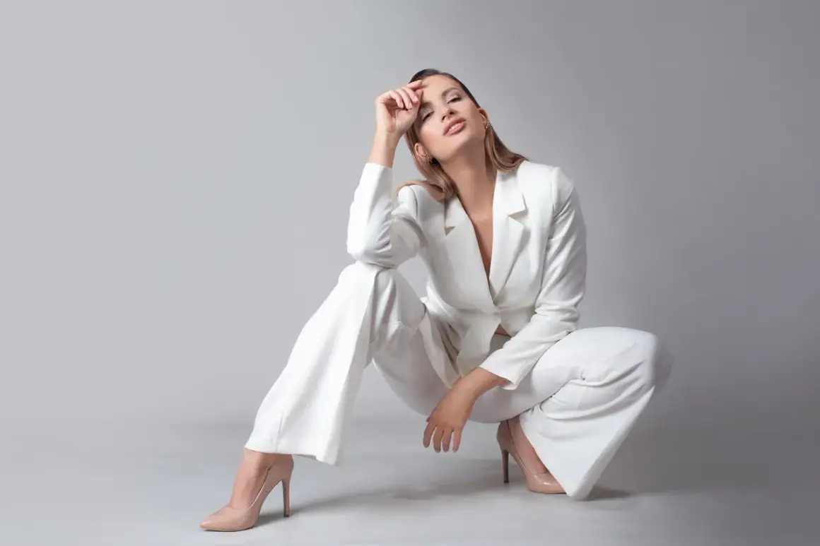 Elegancka kobieta w białym garniturze i cielistych szpilkach. Idealne buty do białego garnituru damskiego podkreślają stylizację.