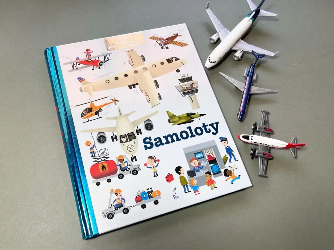 Książki o samolotach z ilustracjami różnych maszyn latających i ludzi pracujących na lotnisku. Obok leżą modele samolotów.