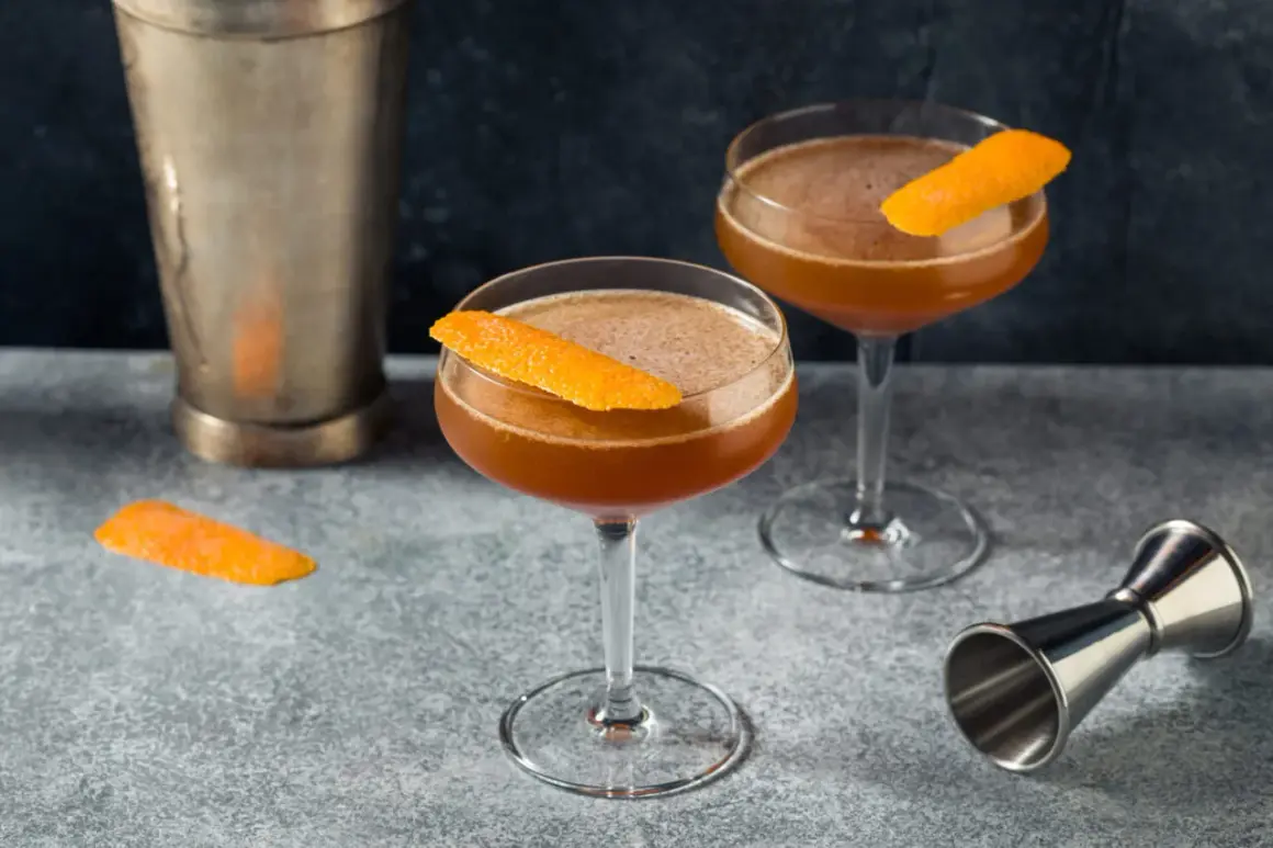 Zwei elegante Cocktails, garniert mit Orangenschale, stehen bereit. Ein "Blood and Sand Cocktail" wartet auf seinen Genuss.