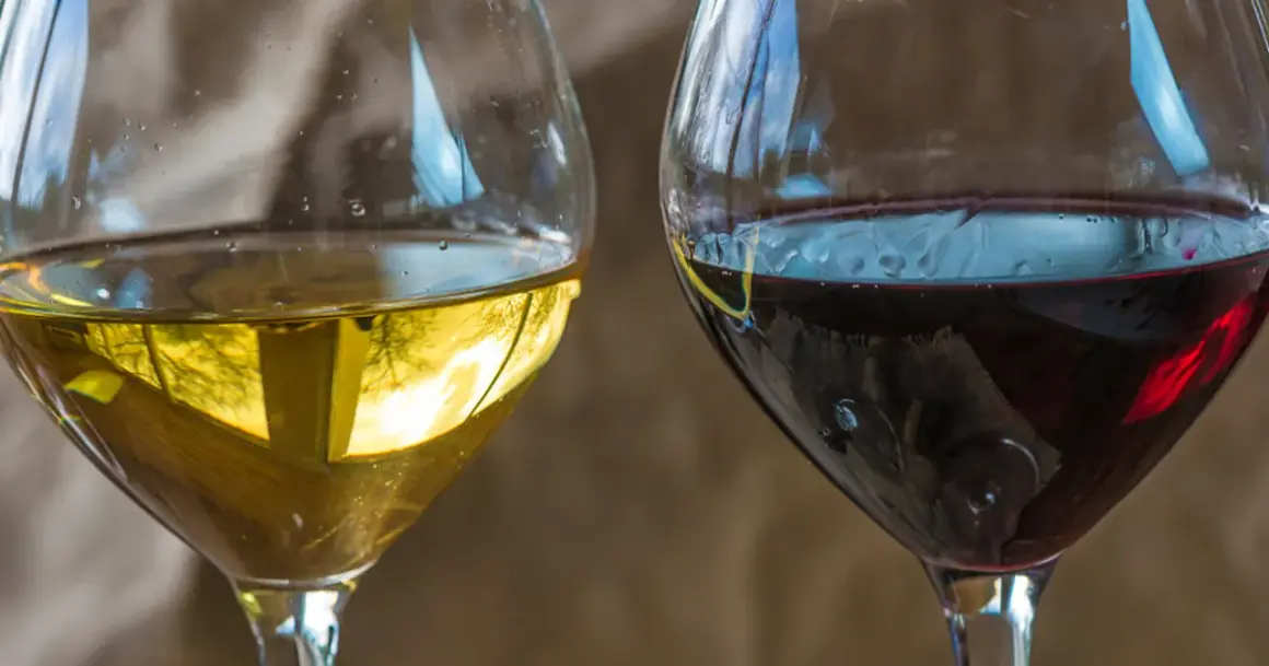 Dwa kieliszki wina, białe i czerwone. Czerwone wino może mieć skutki uboczne, ale oba napoje kuszą smakiem.