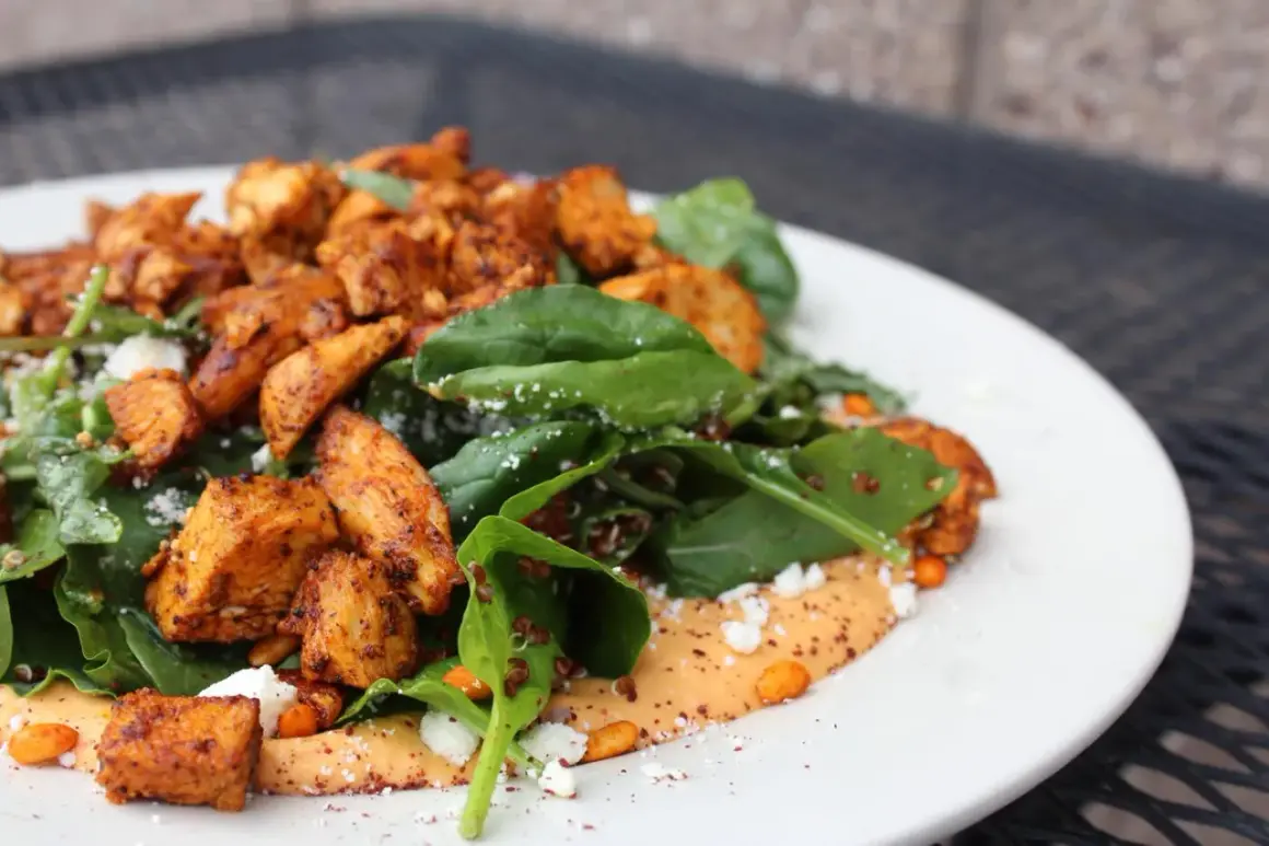 Salade colorée avec poulet épicé, épinards, quinoa et sauce crémeuse. Une alimentation trail parfaite pour l'aventure.