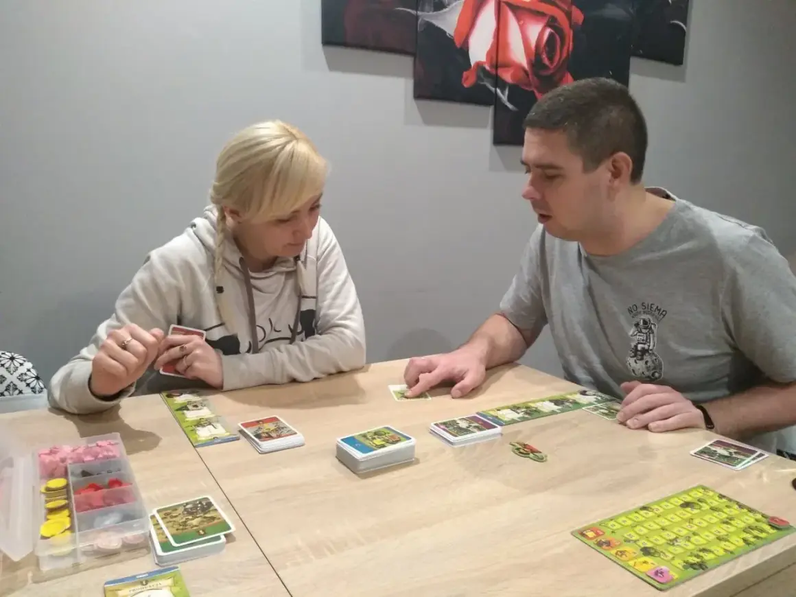 Para dowiedzieć się, jak się gra w planszówkę, obserwuje karty i planszę.