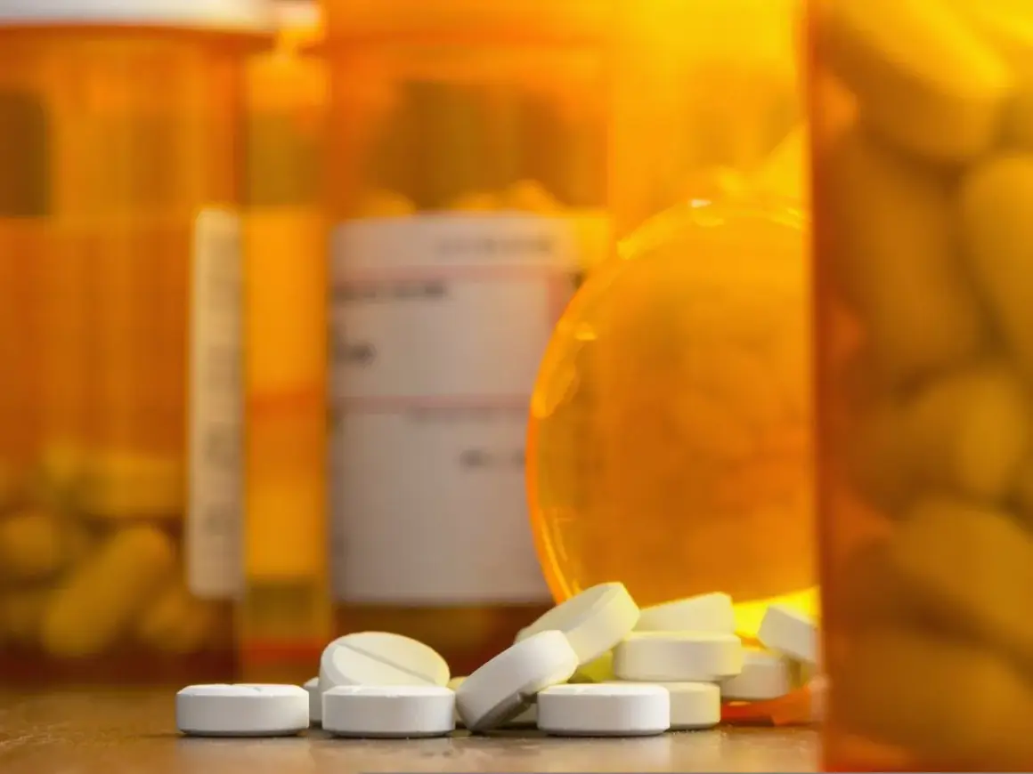 Białe tabletki rozsypane przed pomarańczowymi buteleczkami. Czy to oxycodone, co to za lek?