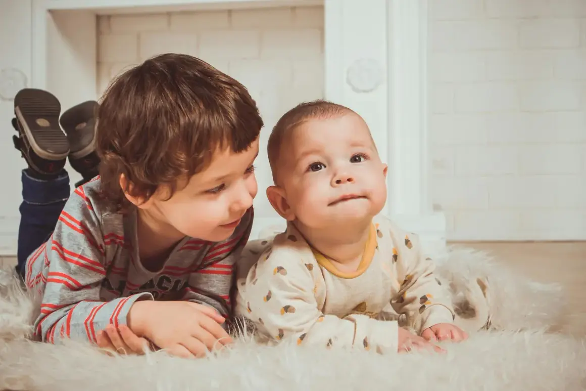 Dwóch braci leży na dywanie. Starszy patrzy na młodszego. Może to przyszli beneficjenci Kinderzuschlag?