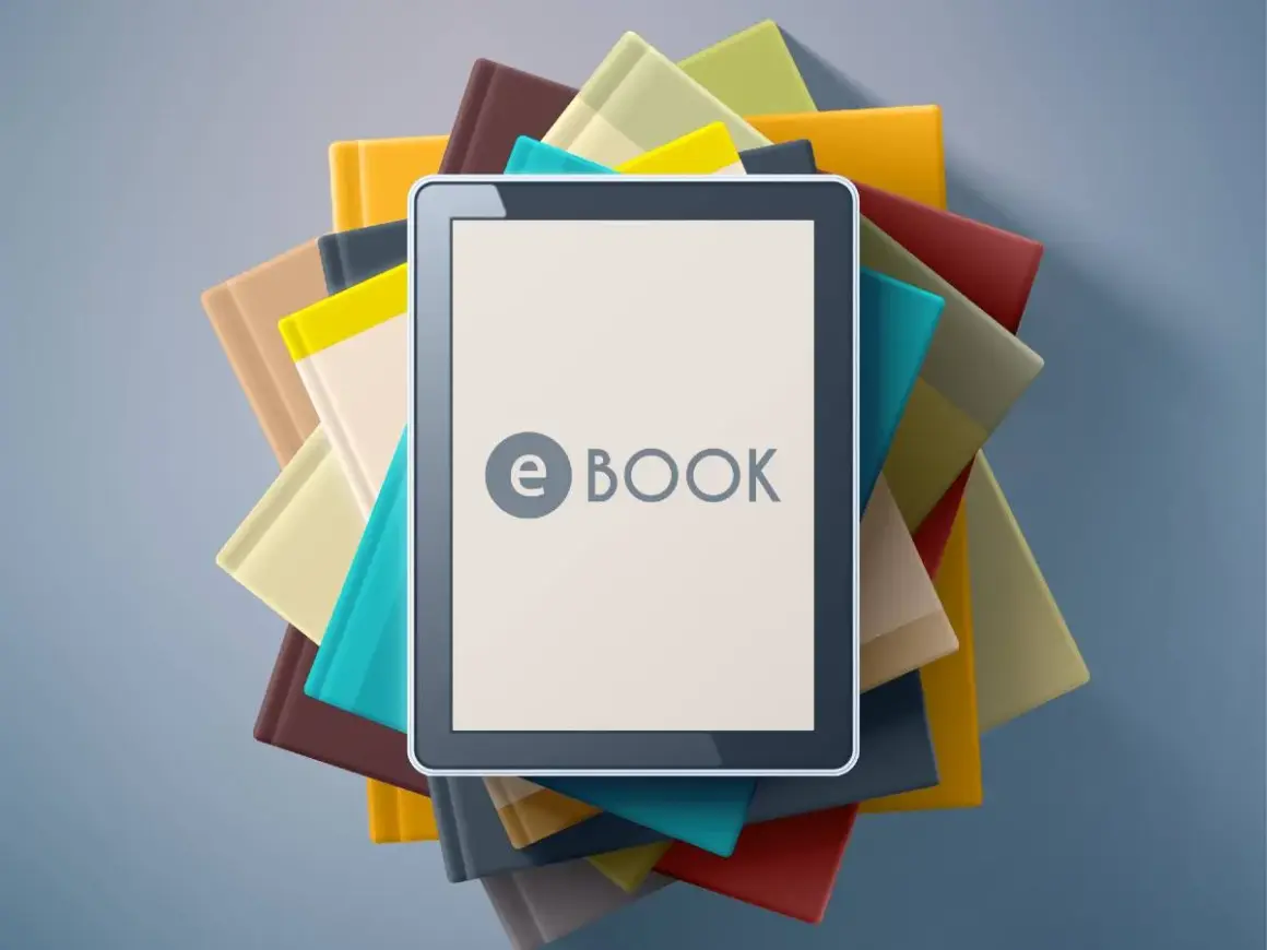 Une tablette affiche "e BOOK" au milieu d'une pile de livres colorés. C'est quoi un ebook ? Une nouvelle façon de lire !