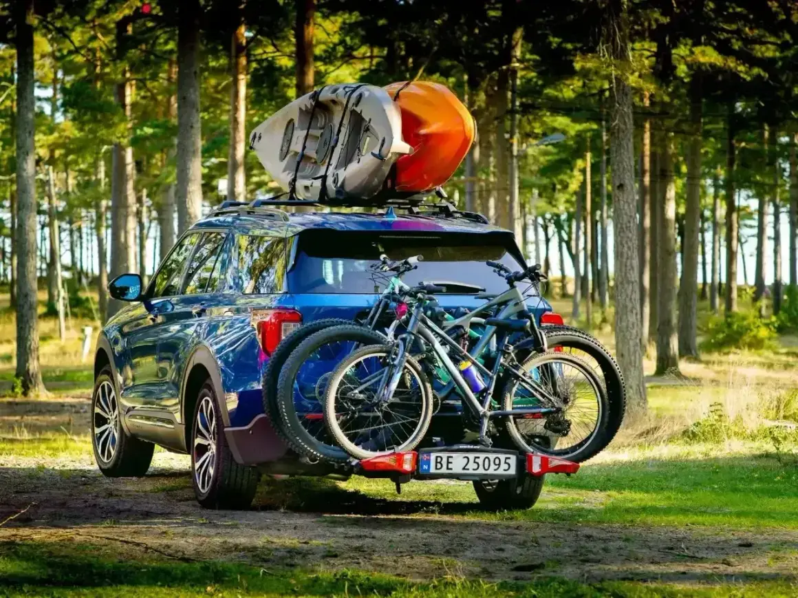 Gotowi na przygodę! Błękitny SUV z rowerami na bagażniku i kajakami na dachu, idealny na pętlę bieszczadzką.