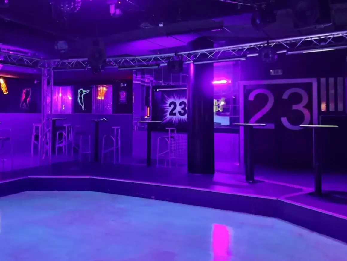 Der leere Dancefloor im Club 23 Rothenburg, beleuchtet in lila und blauem Licht. Hohe Tische und Barhocker stehen bereit.