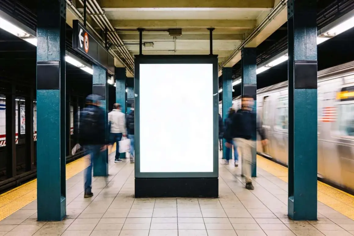 Gente se mueve rápido en el metro de Nueva York, pasando un anuncio en blanco.