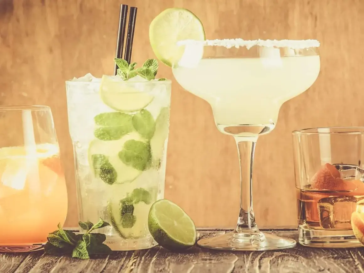 Fyra klassiska drinkar: en Mojito, en Margarita med saltkant, en orange drink och en whisky med apelsinskal.