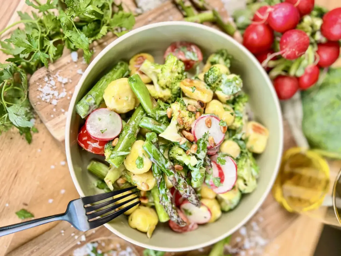Leckerer Gnocchi Salat mit Spargel, Brokkoli, Radieschen und Pinienkernen, garniert mit frischer Petersilie.