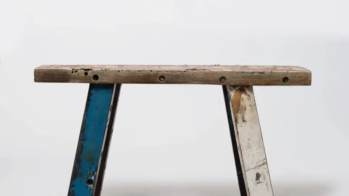 Banc rustique en bois, prêt pour une **rénovation meuble ancien**. Ses pieds bleus et blancs patinés racontent une histoire.