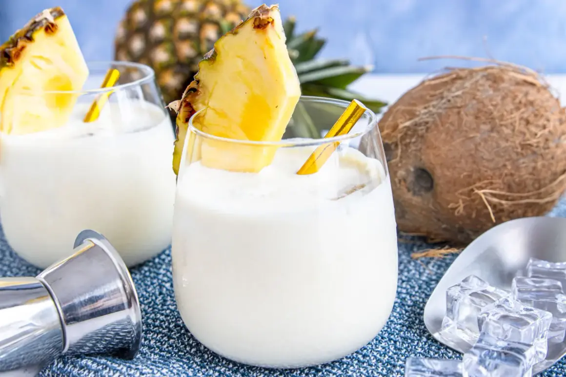 Zwei cremige Kokos-Ananas-Cocktails, garniert mit Ananasstücken, versprechen einen tropischen Genuss. Ein Hauch von "coconut kiss" für heiße Tage.
