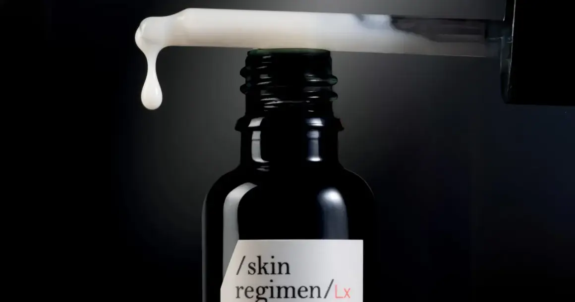 Una goccia di siero cade da un contagocce su una bottiglia scura, un passo essenziale nelle fasi skincare per una pelle radiosa.